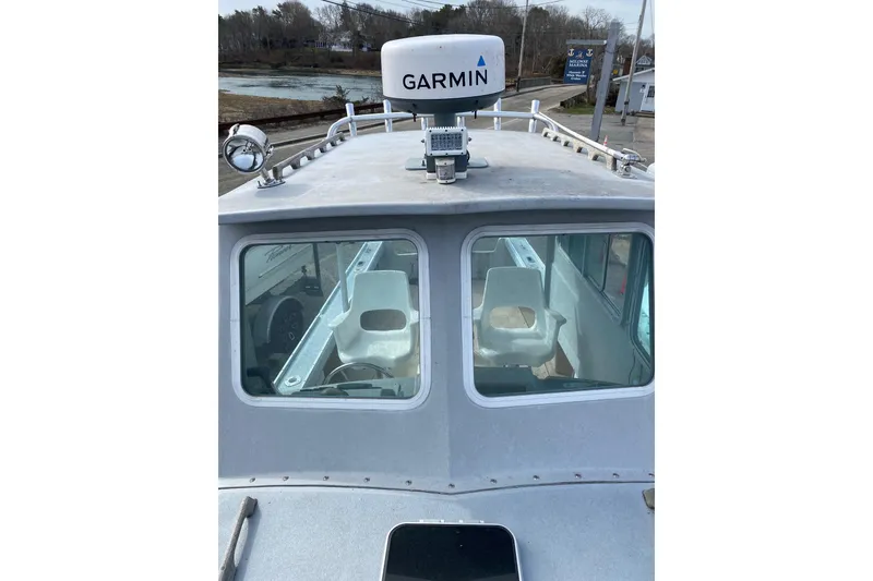Slide: The Image of 1985 SISU Lobster Boat 22' with Garmin radar, docked near a scenic shoreline. - 10