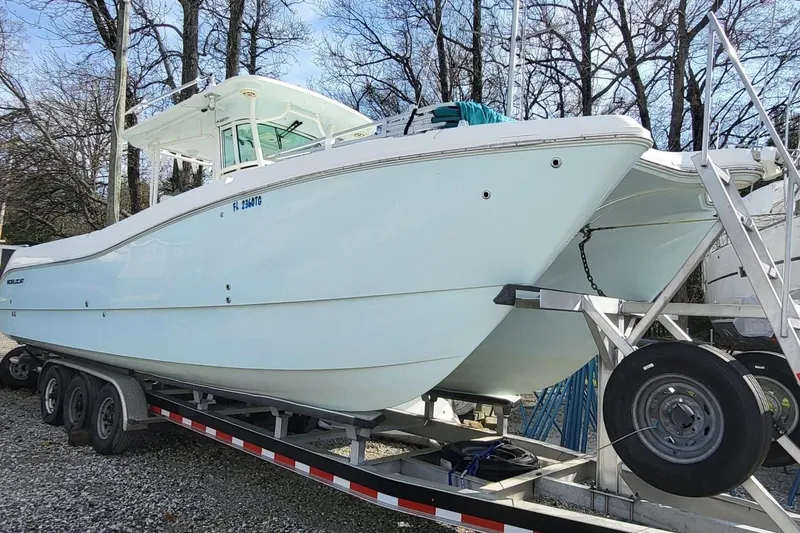 The Image of 2019 World Cat 320 CC boat on trailer, parked outdoors near trees. - 0