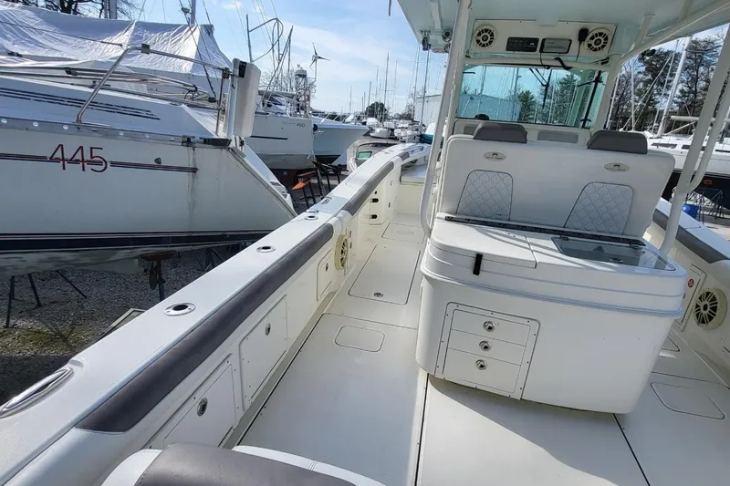 Slide: The Image of 2019 World Cat 320 CC boat interior with seating and storage, docked among other vessels. - 15