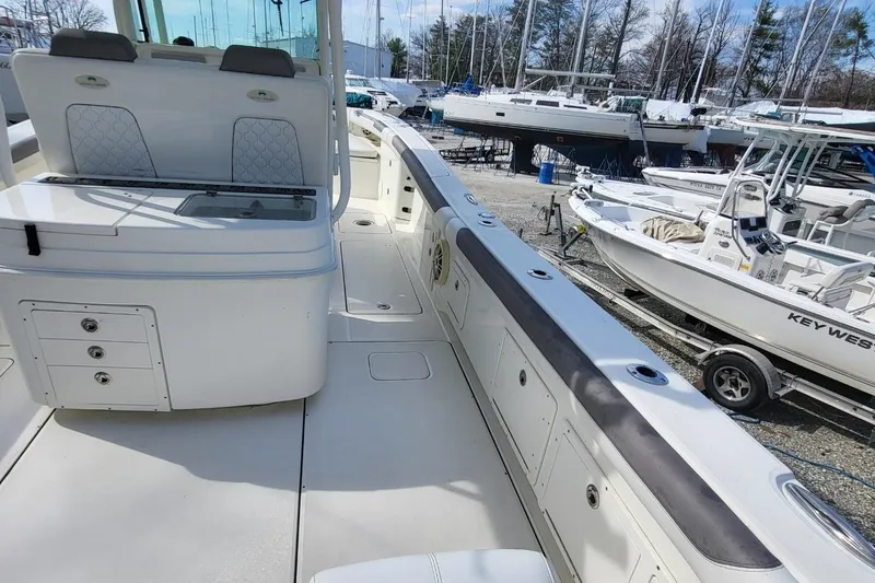 Slide: The Image of 2019 World Cat 320 CC boat interior with seating and storage, docked among other boats. - 16