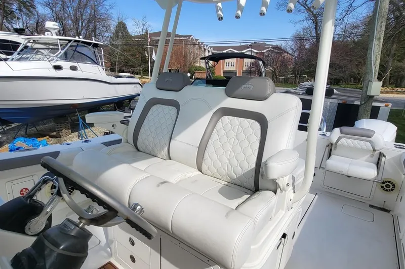 Slide: The Image of 2019 World Cat 320 CC boat interior with white cushioned seating and steering wheel. - 20