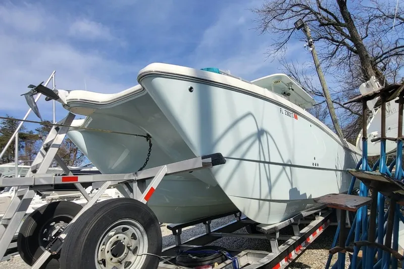 Slide: The Image of 2019 World Cat 320 CC boat on trailer, parked outdoors under clear sky. - 25