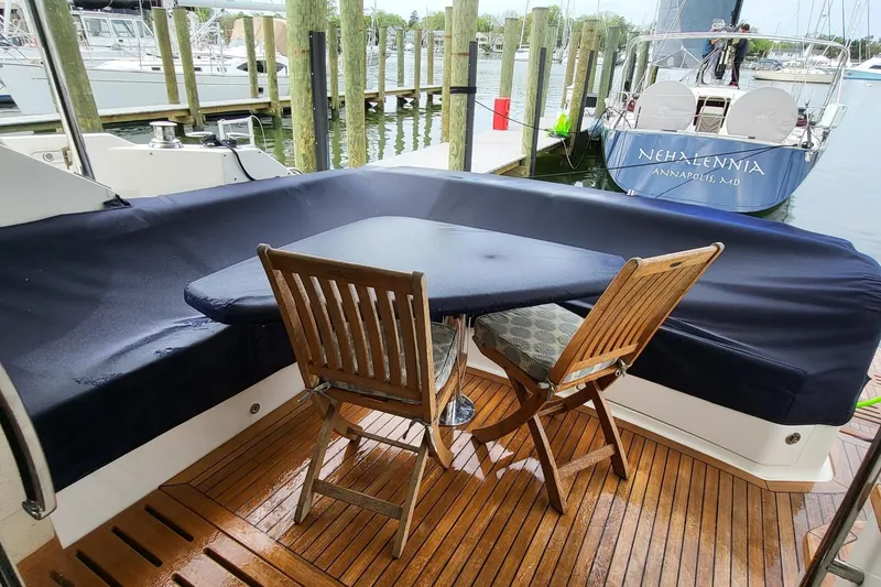 Slide: The Image of 2018 Sea Ray L590 Fly yacht deck with wooden chairs and table, docked at marina. - 24