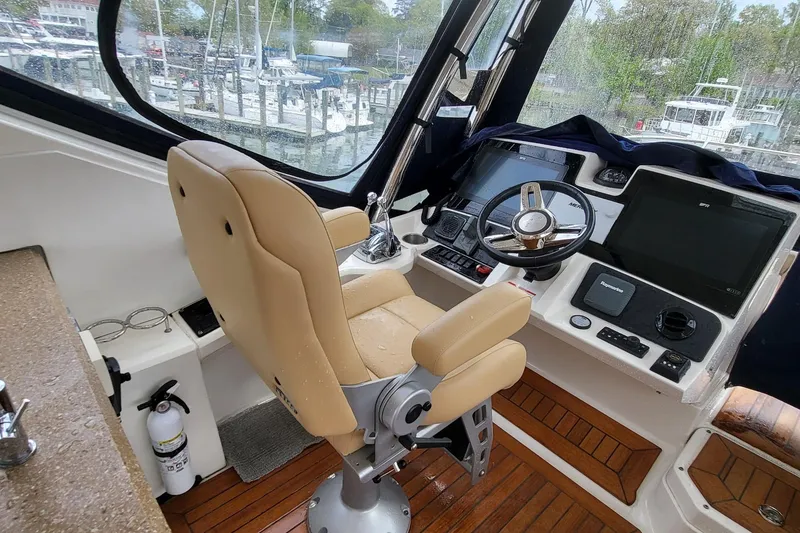 Slide: The Image of 2018 Sea Ray L590 Fly yacht helm with beige captain's chair and advanced navigation controls. - 32