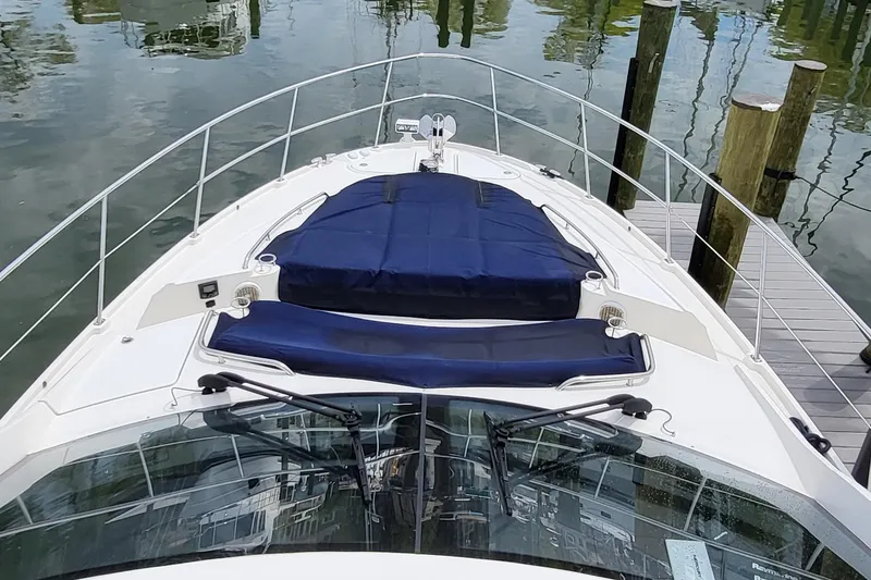 Slide: The Image of 2018 Sea Ray L590 Fly yacht with blue sunbeds on deck, docked by wooden posts. - 37