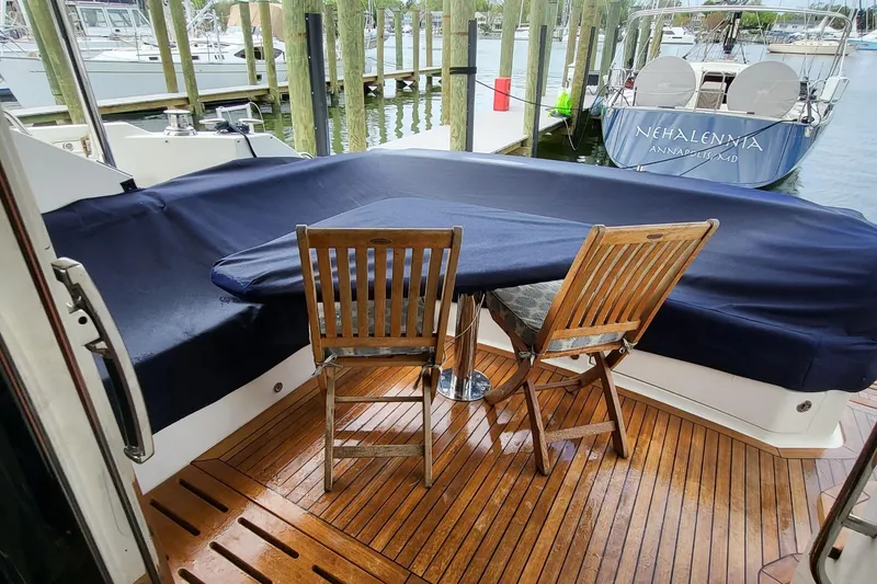 Slide: The Image of 2018 Sea Ray L590 Fly yacht deck with wooden chairs and covered seating area. - 44