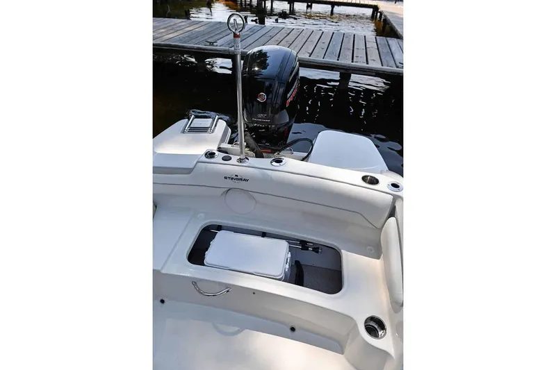 Slide: The Image of Manufacturer Provided Image: 2025 Stingray 191 DC boat interior with motor and dock in background. - 7