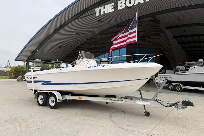 Slide: The Image of 2001 Pro-Line 22 Sport boat on trailer, parked outside a boat dealership with an American flag. - 2