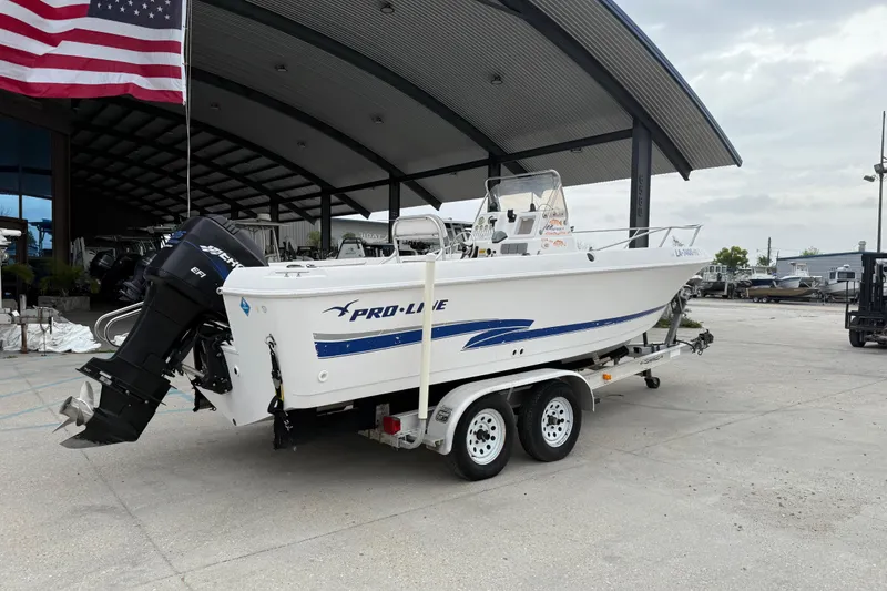 Slide: The Image of 2001 Pro-Line 22 Sport boat on trailer, parked under a large canopy with American flag. - 3
