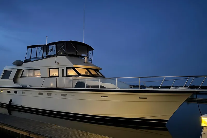 The Image of 1987 Hatteras 54 Motor Yacht docked at twilight, illuminated windows, calm waters. - 0