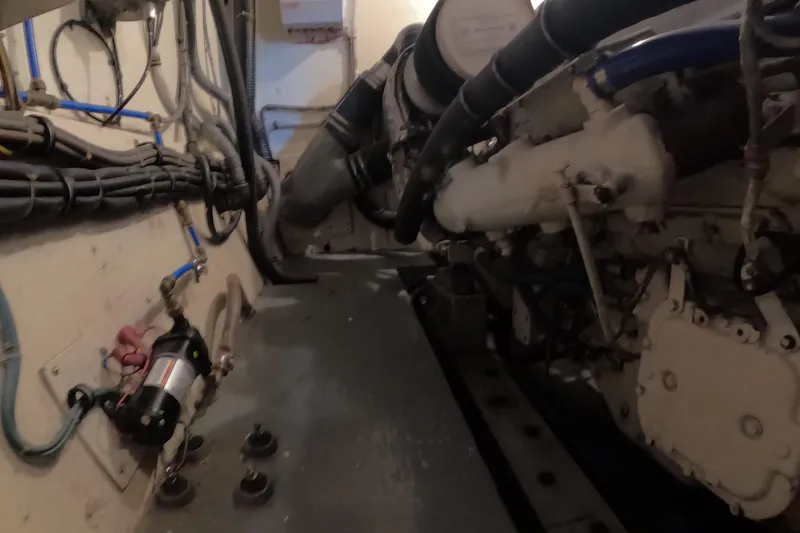 Slide: The Image of Engine room of a 1987 Hatteras 54 Motor Yacht, showcasing mechanical components and wiring. - 102