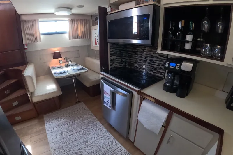 Slide: The Image of 1987 Hatteras 54 Motor Yacht interior with dining area, modern kitchen appliances, and wine storage. - 13