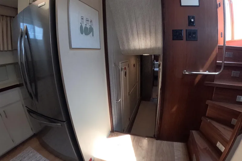 Slide: The Image of Interior of 1987 Hatteras 54 Motor Yacht with modern kitchen and wooden stairs. - 18