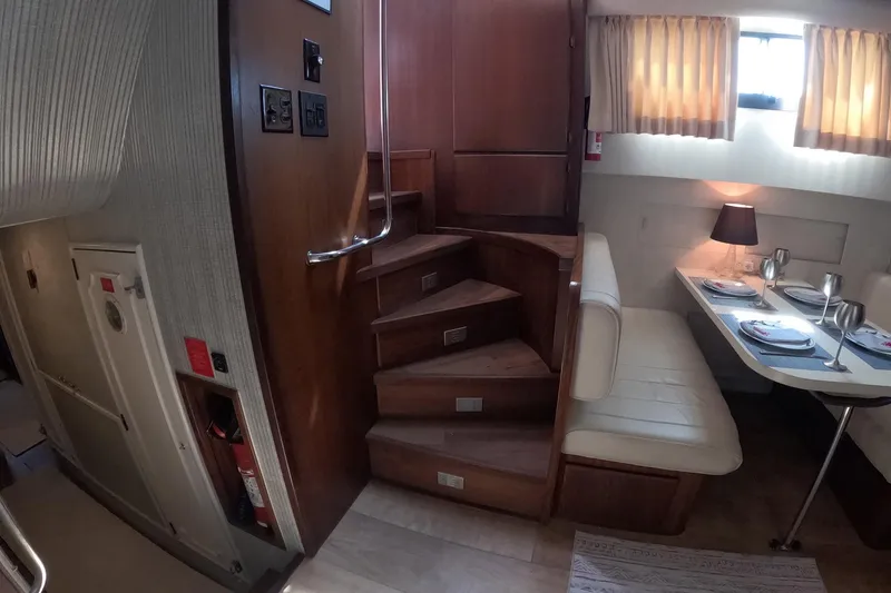 Slide: The Image of Interior of 1987 Hatteras 54 Motor Yacht with dining area and wooden staircase. - 19