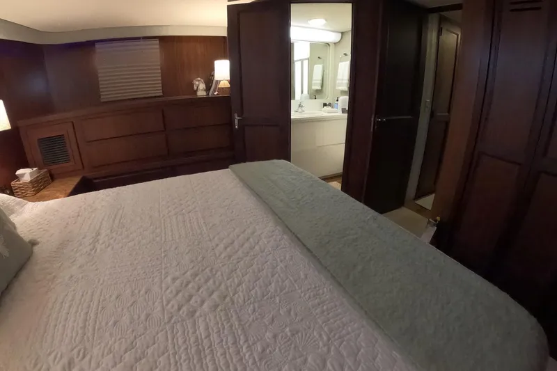 Slide: The Image of Interior of 1987 Hatteras 54 Motor Yacht bedroom with ensuite bathroom, featuring wood paneling. - 29