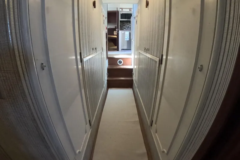 Slide: The Image of Narrow hallway inside 1987 Hatteras 54 Motor Yacht, featuring white walls and wooden steps. - 32
