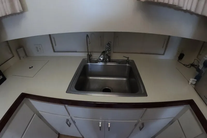Slide: The Image of 1987 Hatteras 54 Motor Yacht kitchen sink with white countertop and cabinets. - 35