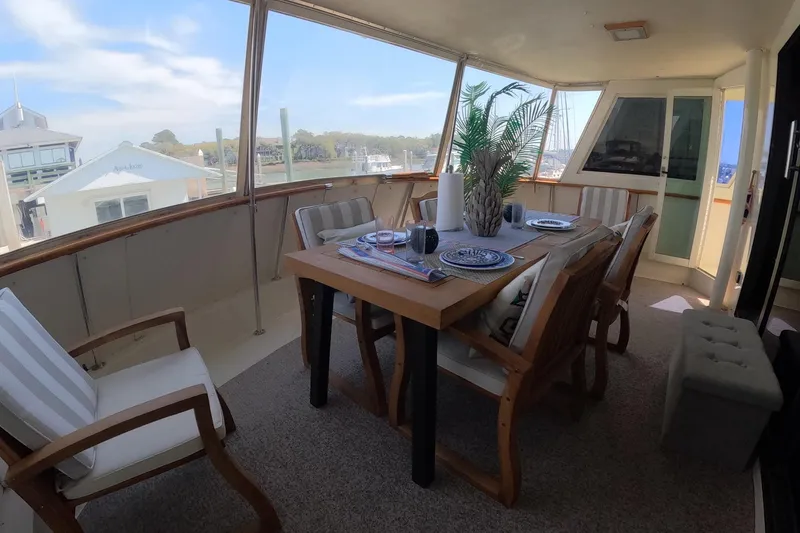 Slide: The Image of 1987 Hatteras 54 Motor Yacht interior with dining setup and scenic marina view. - 39