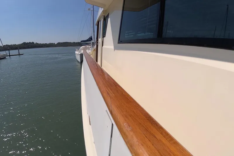 Slide: The Image of 1987 Hatteras 54 Motor Yacht side view with wooden railing on calm water. - 44