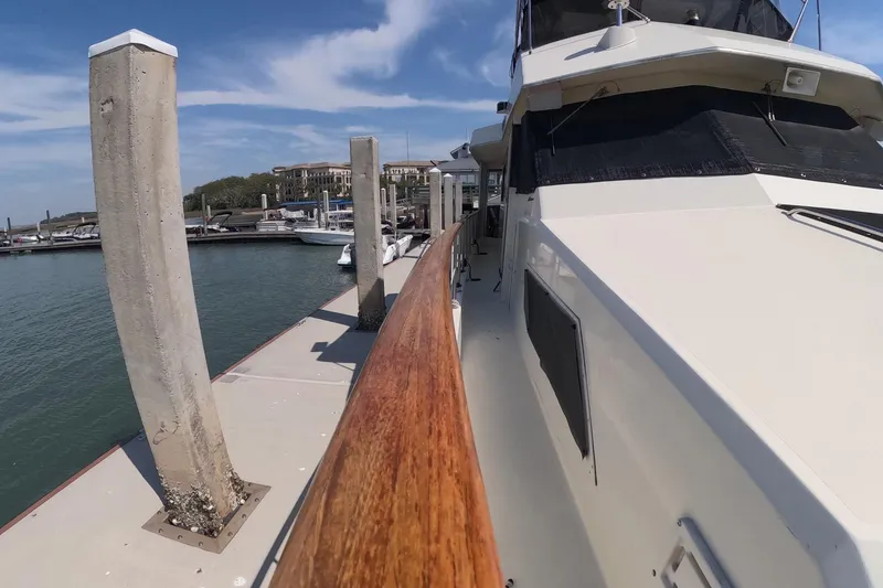 Slide: The Image of 1987 Hatteras 54 Motor Yacht docked at marina under blue sky. - 46