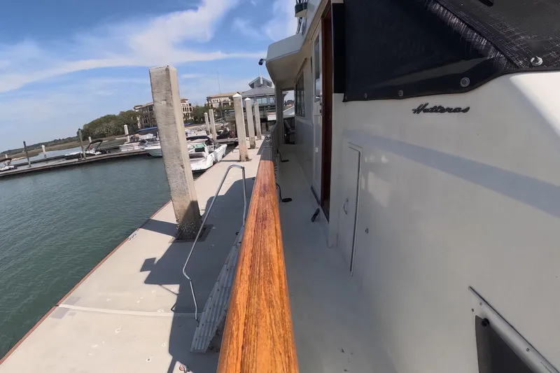 Slide: The Image of 1987 Hatteras 54 Motor Yacht docked at marina, showcasing sleek design and wooden railings. - 47