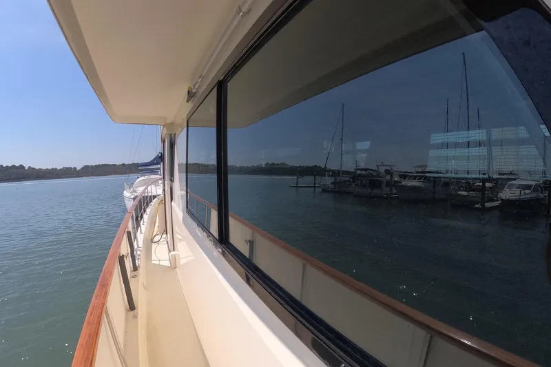 Slide: The Image of 1987 Hatteras 54 Motor Yacht reflecting marina view on calm water. - 49