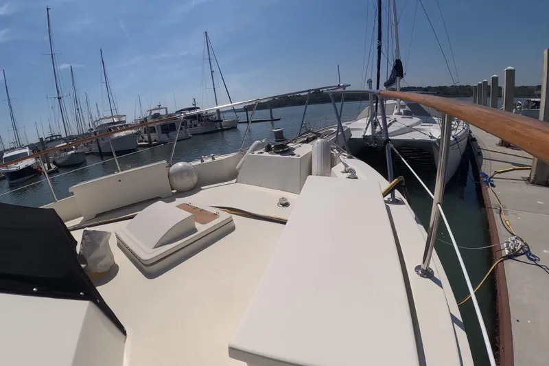 Slide: The Image of 1987 Hatteras 54 Motor Yacht docked at marina, surrounded by sailboats under clear blue sky. - 50
