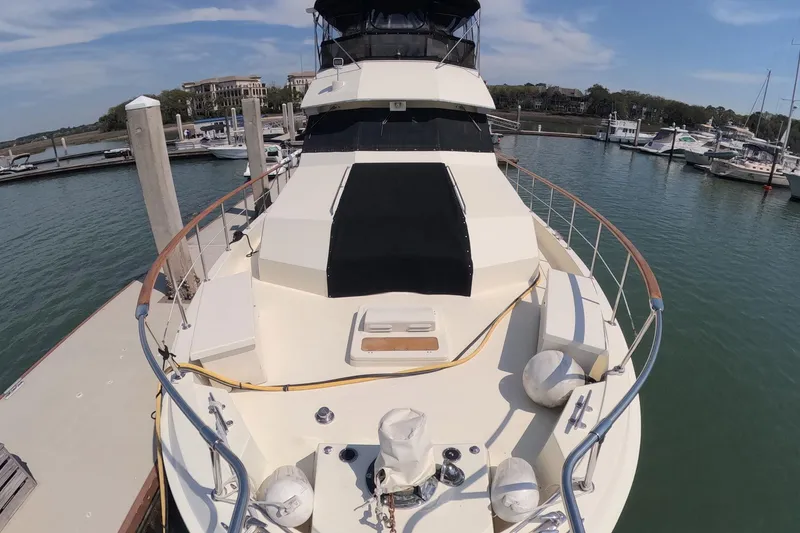 Slide: The Image of 1987 Hatteras 54 Motor Yacht docked at marina, showcasing spacious deck and sleek design. - 51