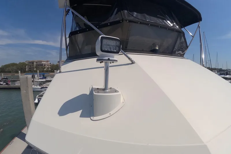 Slide: The Image of 1987 Hatteras 54 Motor Yacht bow with spotlight, docked under clear blue sky. - 53
