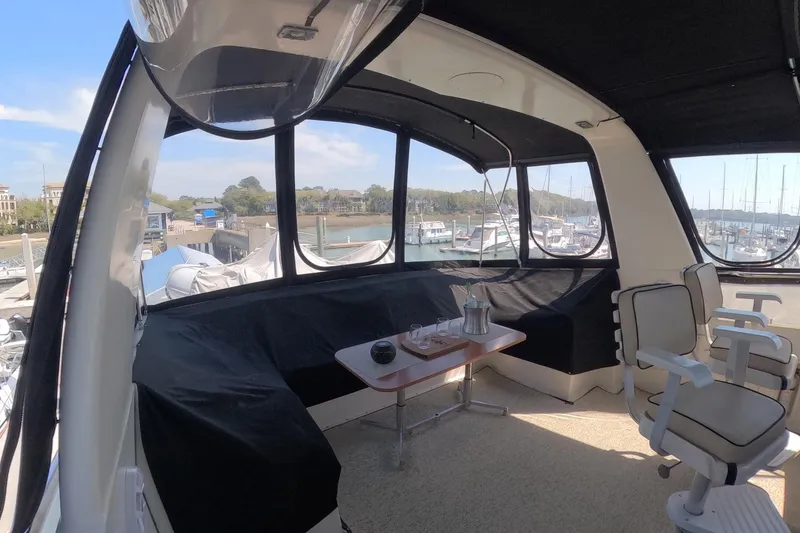 Slide: The Image of 1987 Hatteras 54 Motor Yacht interior with seating, table, and marina view. - 56