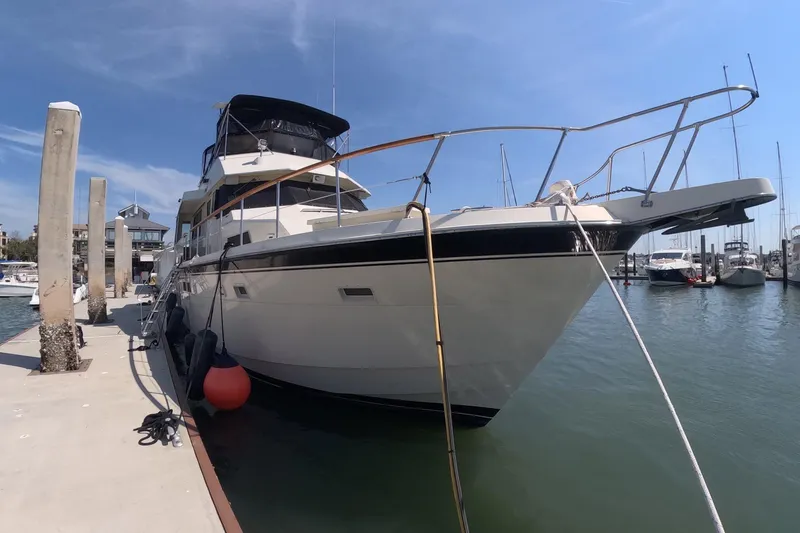 Slide: The Image of 1987 Hatteras 54 Motor Yacht docked at marina under clear blue sky. - 62