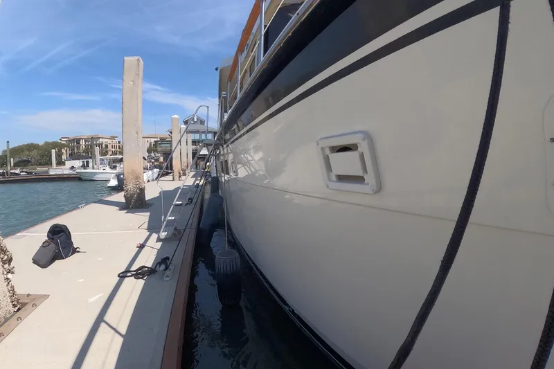 Slide: The Image of 1987 Hatteras 54 Motor Yacht docked at marina under clear blue sky. - 63