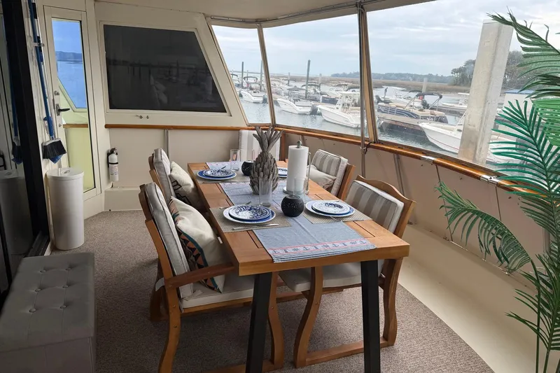 Slide: The Image of Dining area on 1987 Hatteras 54 Motor Yacht with elegant table setting and marina view. - 80