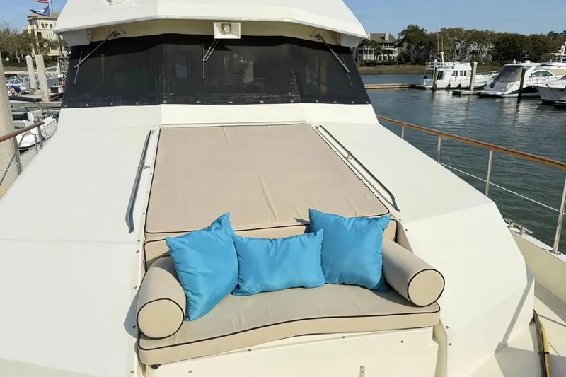 Slide: The Image of 1987 Hatteras 54 Motor Yacht with cushioned deck seating and blue pillows at marina. - 81