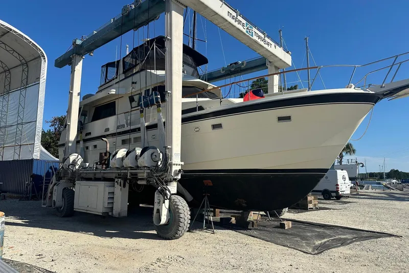 Slide: The Image of 1987 Hatteras 54 Motor Yacht on a lift at a marina, under clear blue skies. - 83
