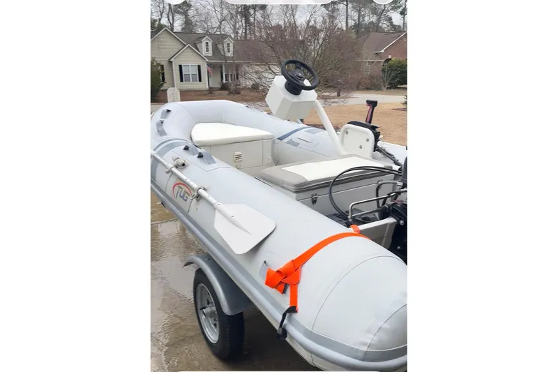 Slide: The Image of Inflatable boat on trailer, featuring steering console and paddles, parked in residential area. - 86