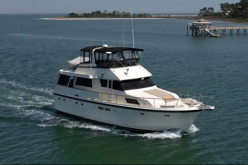 Slide: The Image of 1987 Hatteras 54 Motor Yacht cruising on open water near a dock. - 88