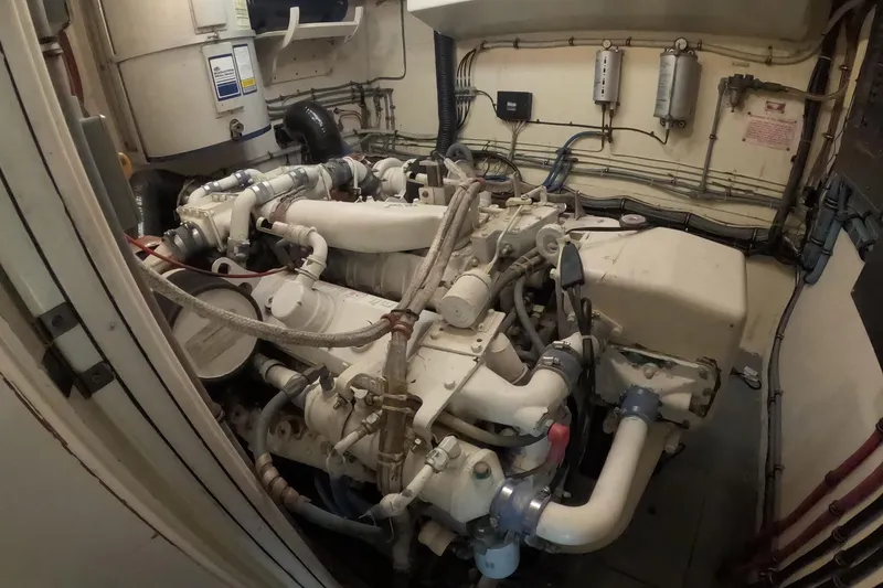 Slide: The Image of Engine room of a 1987 Hatteras 54 Motor Yacht, showcasing complex machinery and piping. - 93