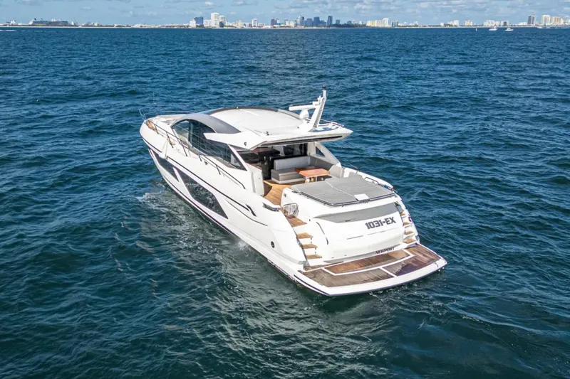 Slide: The Image of 2020 Sunseeker Predator 74 yacht cruising on open water with city skyline in background. - 5
