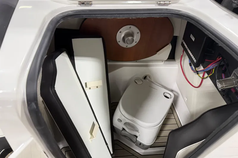Slide: The Image of Interior storage compartment of 2026 Stingray 212 SC boat with portable toilet and accessories. - 12
