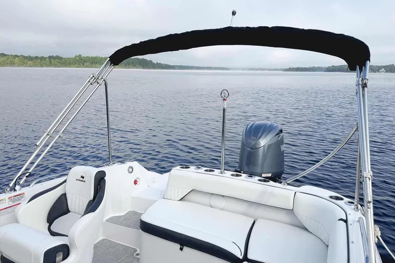 Slide: The Image of Manufacturer Provided Image: 2026 Stingray 212 SC boat with seating and canopy on a calm lake. - 17