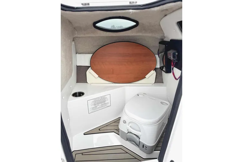 Slide: The Image of Manufacturer Provided Image: 2026 Stingray 212 SC boat interior with portable toilet and wooden table. - 18