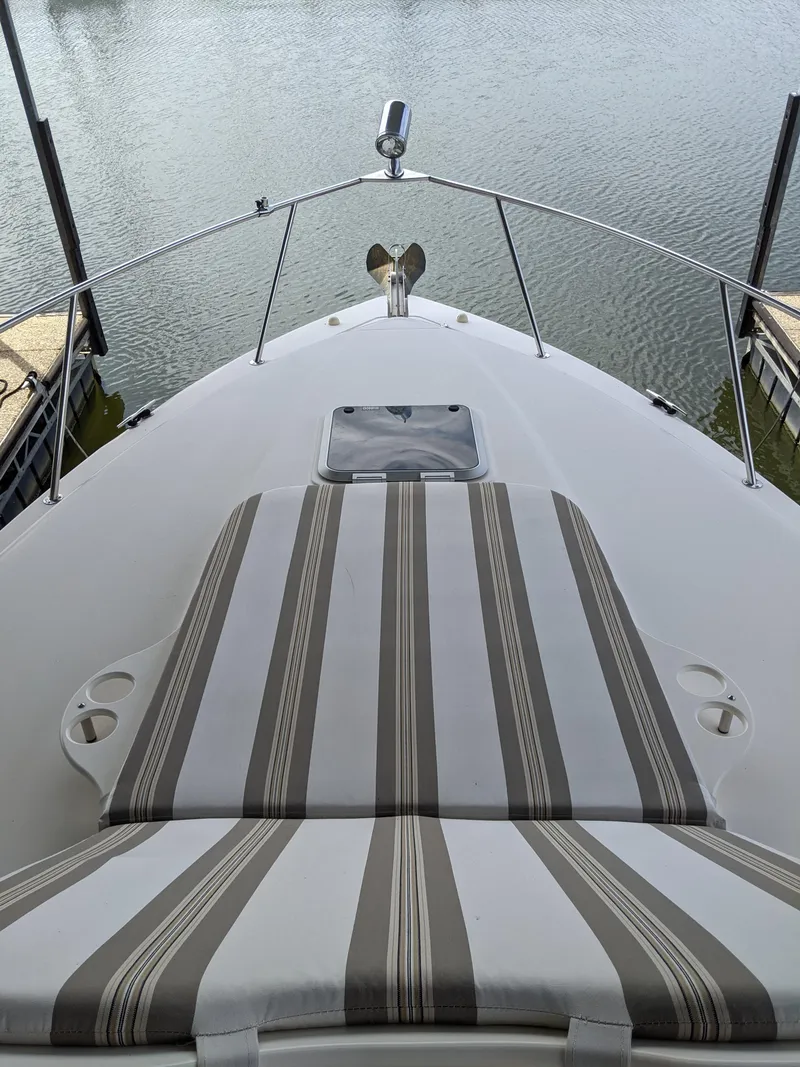 Slide: The Image of 2004 Rinker Fiesta Vee 410 boat bow with striped sun pad, docked on calm water. - 13
