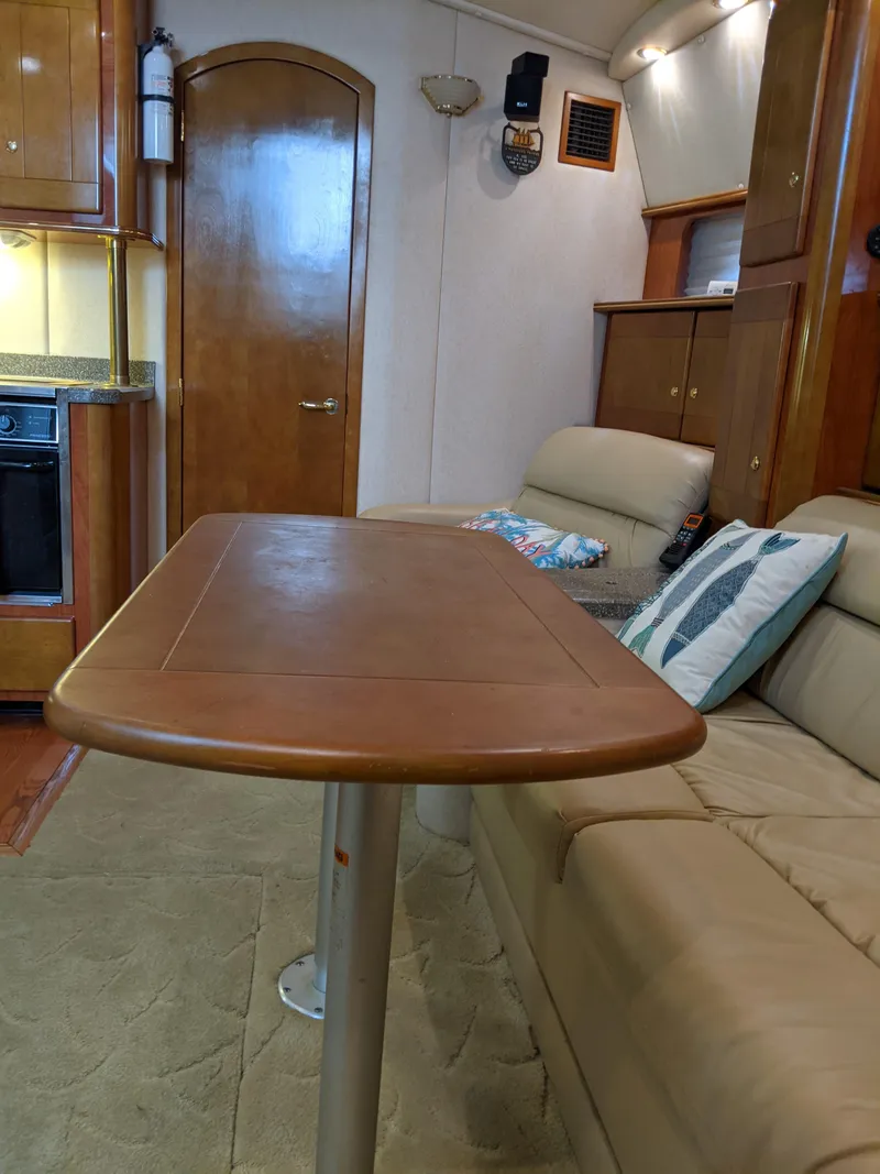 Slide: The Image of 2004 Rinker Fiesta Vee 410 interior with wooden table and beige seating. - 26