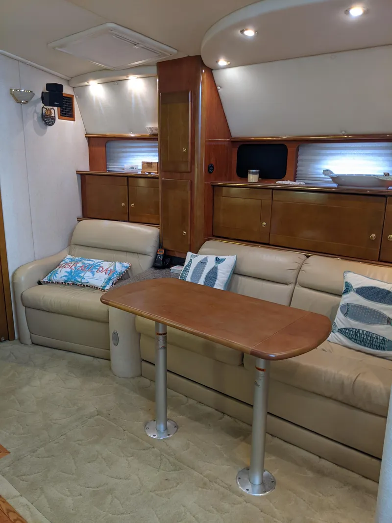 Slide: The Image of 2004 Rinker Fiesta Vee 410 interior with beige seating, wooden table, and cabinets. - 27