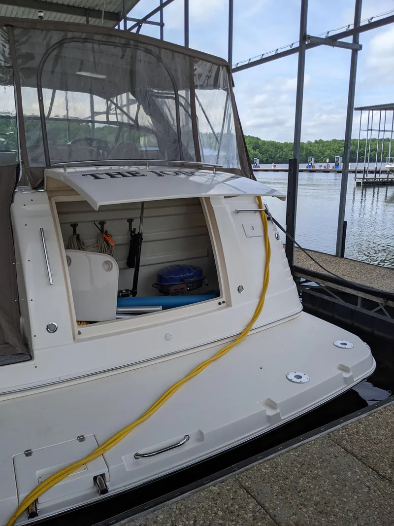 Slide: The Image of 2004 Rinker Fiesta Vee 410 docked, showing open storage compartment and marina background. - 7