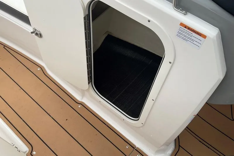Slide: The Image of Open storage compartment on 2023 Chaparral 23 SSi boat with teak-style flooring. - 30