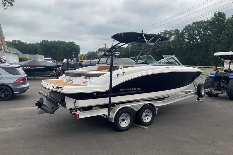Slide: The Image of 2023 Chaparral 23 SSi boat on trailer, parked outdoors near vehicles and trees. - 9