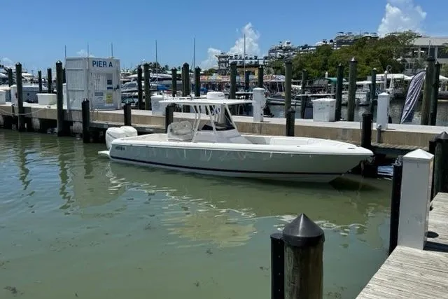 The Image of 2015 Intrepid 327 Center Console boat docked at marina under clear blue sky. - 0
