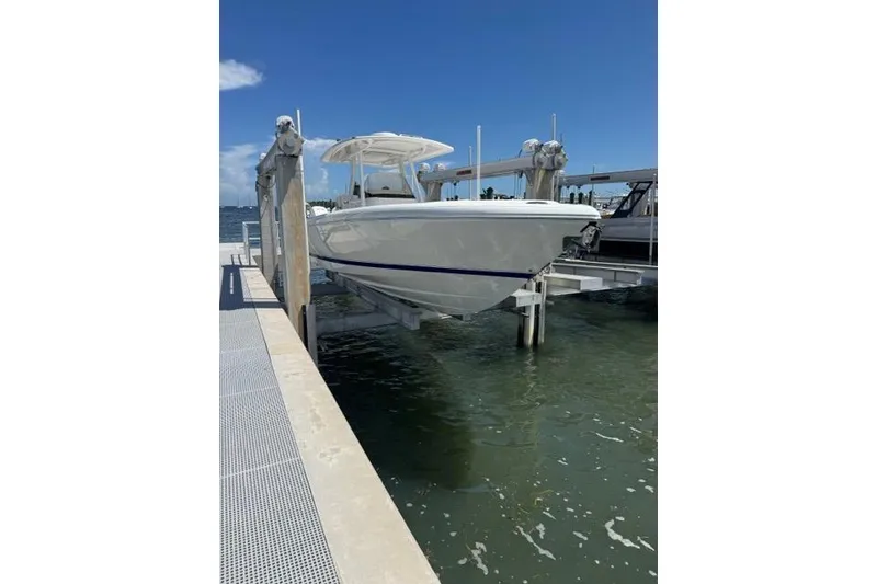 Slide: The Image of 2015 Intrepid 327 Center Console boat on lift by dock, sunny day. - 3
